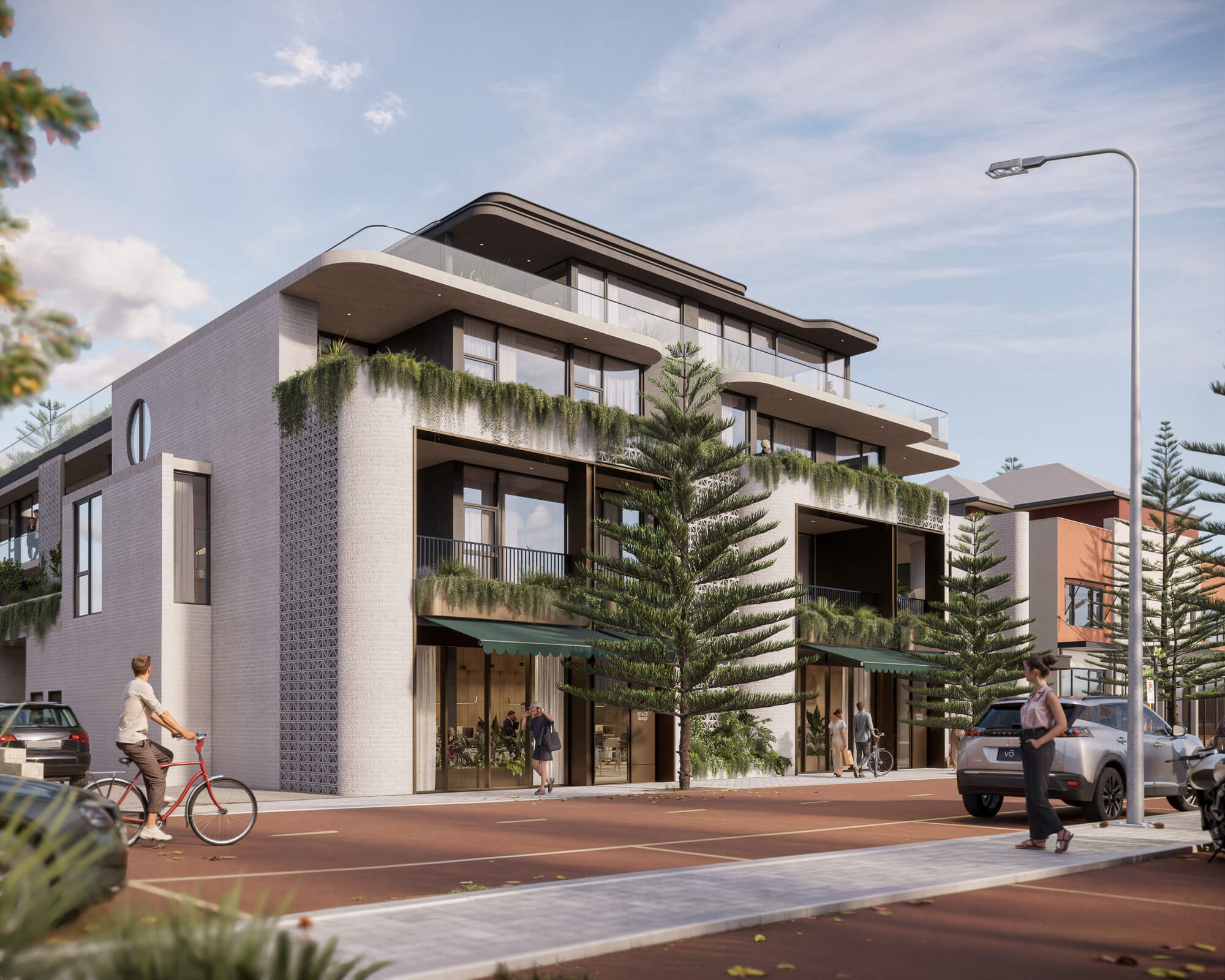 Modern three-story building with balconies and greenery along a street with pedestrians, a cyclist, and parked cars.